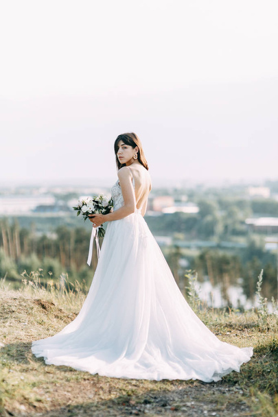 Bride with long dress in nature with sunset. A stylish wedding in the European style of fine art.  - Φωτογραφία, εικόνα