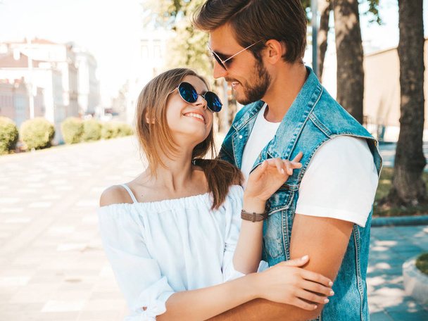 Smiling beautiful girl and her handsome boyfriend. Woman in casual summer dress and man in jeans clothes. Happy cheerful family. Female having fun on the street background.Hugging couple in sunglasses - Photo, image