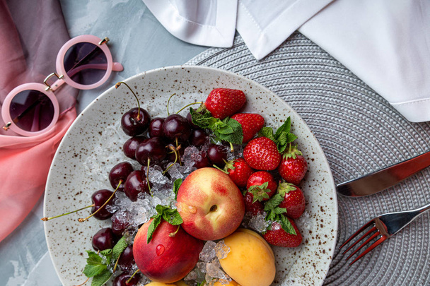 Healthy fruit platter, strawberries, apples, peaches, apricots on a dark gray wooden table, top view, close-up, selective focus. - Foto, imagen