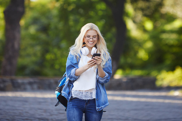 Front view of young excited female student receiving good news on line in a mobile phone in an university campus or street. Concept of winner - Photo, Image