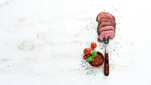 Beef steak on a fork. On a wooden background. Top view. Free space for your text. - Valokuva, kuva