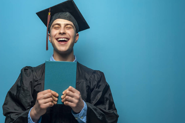 Graduate man with holding blue diploma - Foto, afbeelding