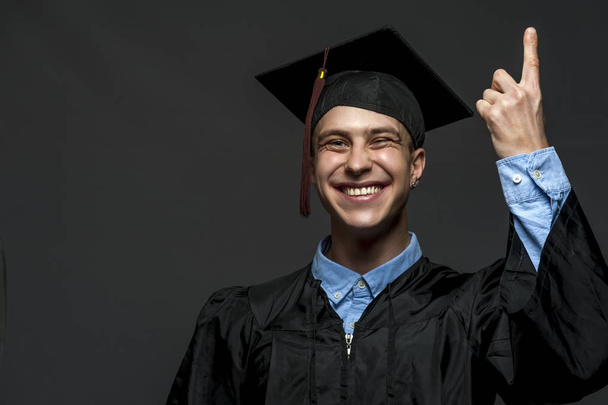 Portrait of graduate adult male student in black graduation gown with hat - Foto, immagini