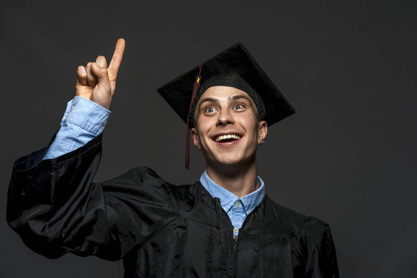 Portrait of graduate adult male student in black graduation gown with hat - Photo, Image