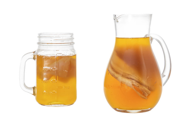 Σπιτικά ποτά με ζύμωση κομπούτσα σε γυάλινη κανάτα και βάζο. Απομονωμένη σε λευκό φόντο - Φωτογραφία, εικόνα