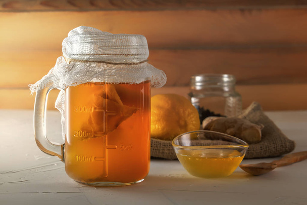 hausgemachtes fermentiertes Getränk Kombucha im Glas mit Zitrone, Honig und Ingwer auf einem Holztisch. Nahaufnahme - Foto, Bild