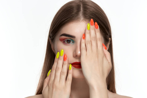 Closeup portrait of beautiful young woman with bright color make-up holding hands with bright  manicure close to face - Φωτογραφία, εικόνα