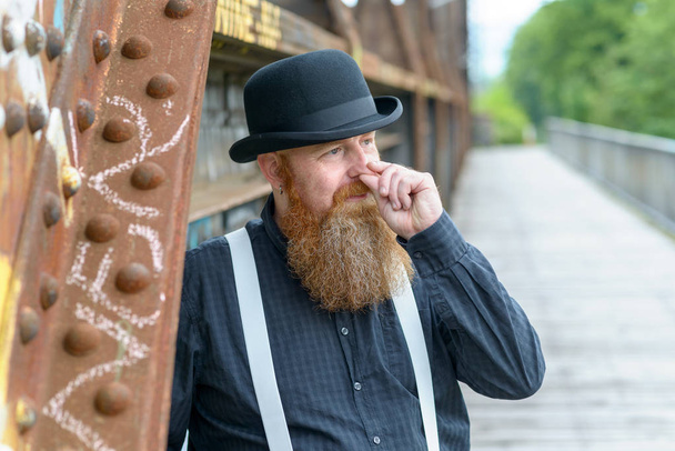 Bearded Man staande buitenshuis wrijven zijn neus - Foto, afbeelding