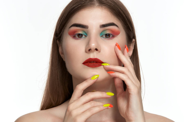 Portrait rapproché de belle jeune femme avec maquillage de couleur vive tenant la main avec manucure lumineuse près du visage
 - Photo, image