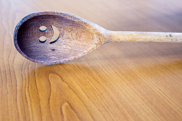 Wooden smiley face spoon on wooden background - Valokuva, kuva