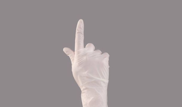 Mano usando guantes de látex haciendo gestos hacia arriba en gris
 - Foto, Imagen