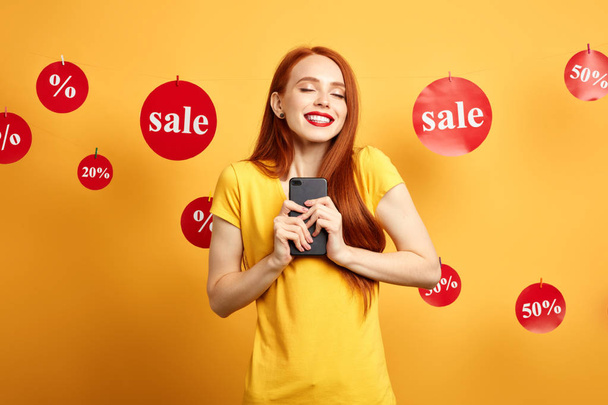 girl rejoicing at her new mobile phone which she has bought during the sale - Фото, изображение