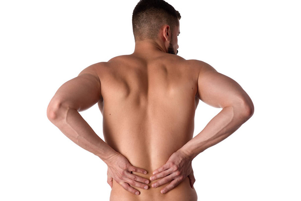 Young man with back pain. The athlete clings to a sore back. Man hurt his back. Sports medicine concept - Photo, Image