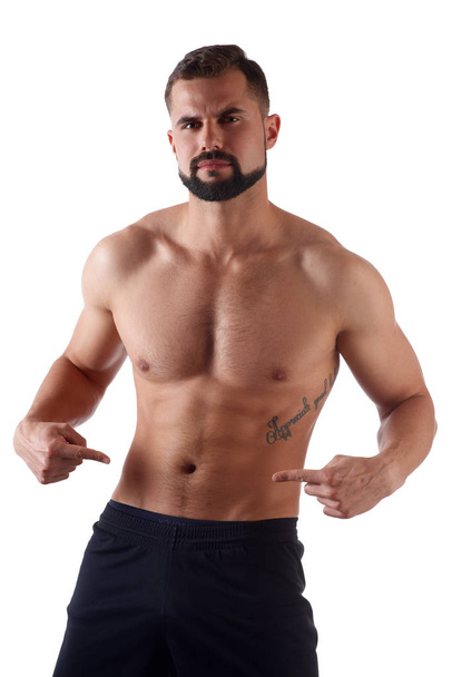 Athlete with a strong torso shows fingers on the cubes on his stomach. Muscular man shows his abs, isolated on white background - Fotoğraf, Görsel