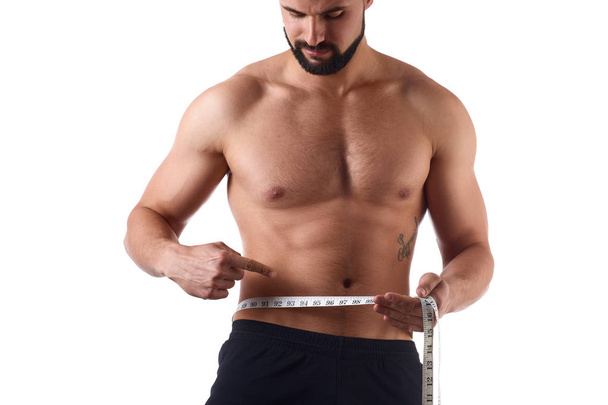 Muž se svalovým tělem, který měří své ABS. silný svalnatý muž na izolovaném pozadí - Fotografie, Obrázek