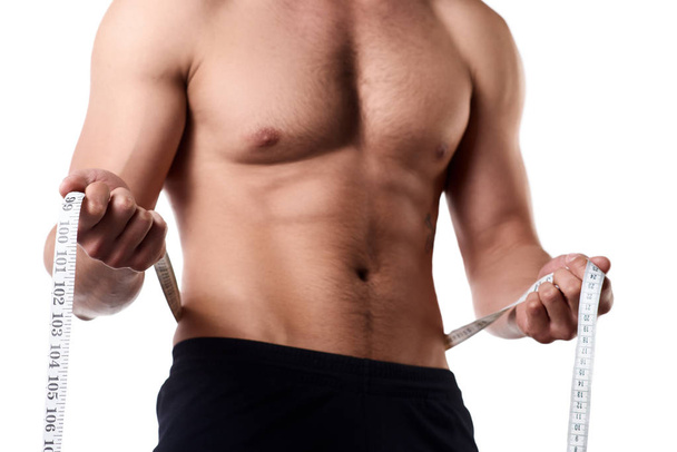 Man with a muscular body measuring his abs. Strong muscular man on isolated background - Foto, immagini