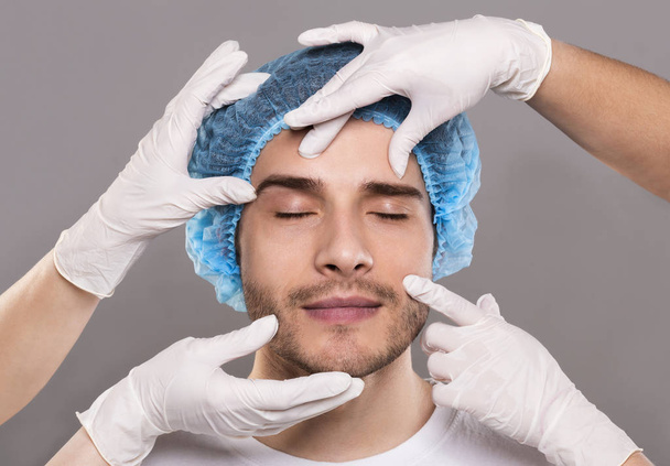 Οι γιατροί δίνουν γάντια ελέγχοντας το πρόσωπο του νεαρού άντρα - Φωτογραφία, εικόνα
