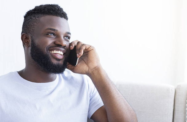 Cheerful young black man talking on smartphone - Fotó, kép