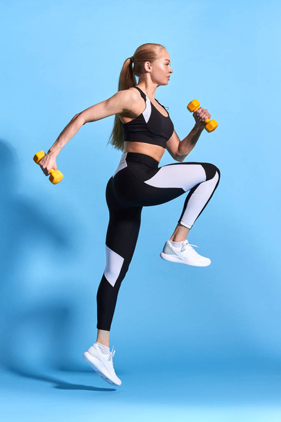fit strong blonde woman doing exercises with dumbbells - Foto, afbeelding