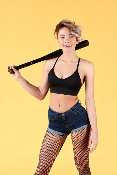 positive cute fair-haired woman holding baseball bat or racket - Fotó, kép