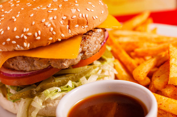 Cierra Tasty Cheeseburger en el restaurante. Pan de sésamo, carne Patty, tomate, lechuga y pepinillo. Servido con papas fritas
 - Foto, imagen