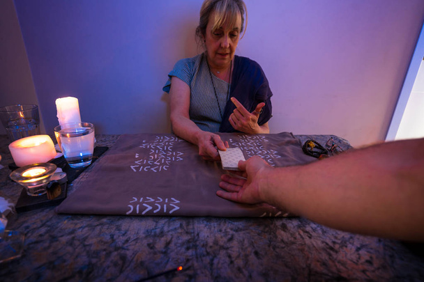 Κάρτες Ταρώ. Μια γυναίκα κάθεται κοντά σε ένα γραφείο με κάρτες Ταρώ και κεριά. Μαντεία και διόραση. - Φωτογραφία, εικόνα