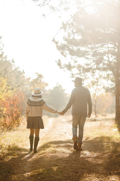Lovely hipster couple looking at each other. Couple wearing beautiful hats and sweaters. Lifestyle, happy couple of two play on a sunny day in the park. The concept of youth, love and lifestyle. Sunset in autumn  - Foto, afbeelding