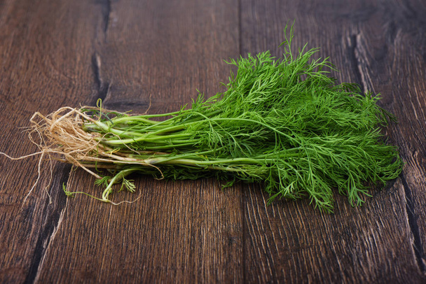 Fresh dill with roots on wooden table. Rustic style. - Foto, imagen