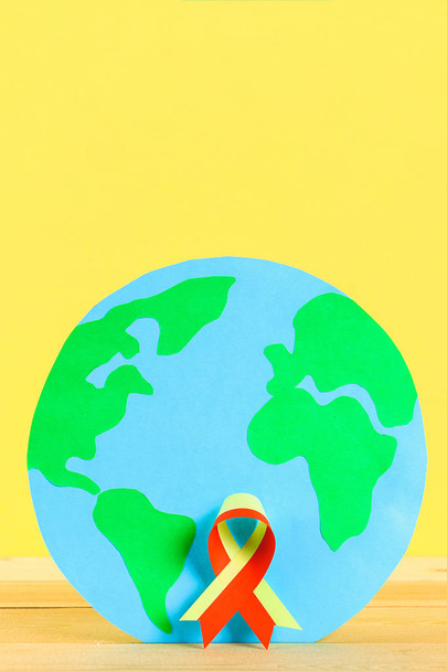 World Hepatitis Day. June 28th. Red yellow ribbon and planet earth on a wooden table - Foto, imagen