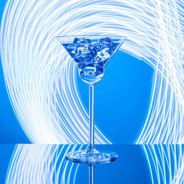 Γυαλί με κοκτέιλ στο γυάλινο τραπέζι στα φώτα νέον φόντο - Φωτογραφία, εικόνα