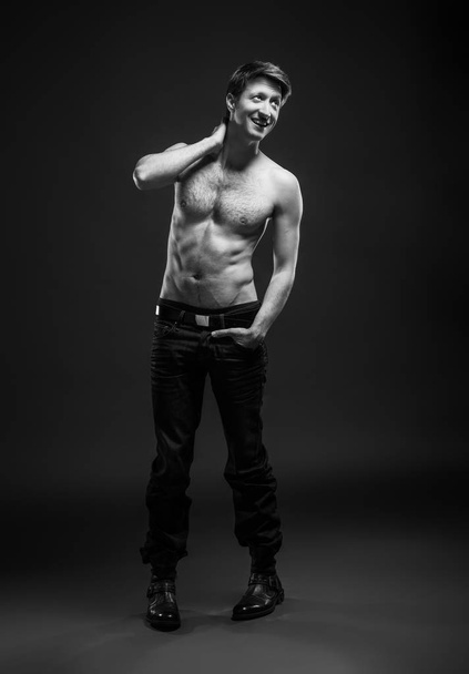 Full length portrait of a sexy young man in jeans and shirtless posing at studio. - Foto, Imagem