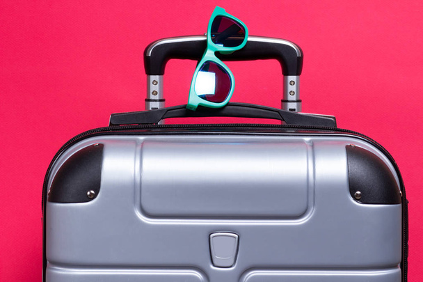 Suitcase with sunglasses on pink background. Summer travel conce - Zdjęcie, obraz