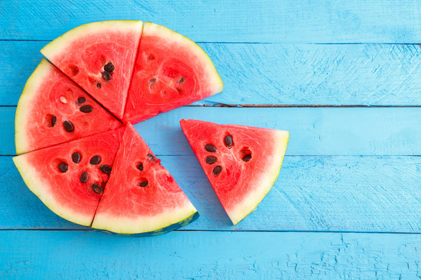 red scarlet watermelon pieces on blue wooden vintage background. - Photo, Image