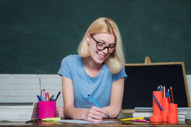 University student going to college. Teacher in classroom. Student preparing for test or exam. Young woman sitting at table doing assignments library. Young teacher. - Valokuva, kuva