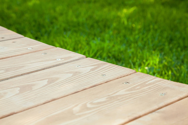 Wooden table in diagonal on the image with blurred summer green background - Fotografie, Obrázek