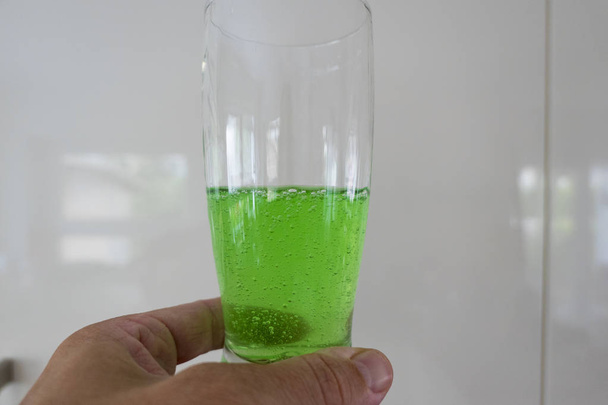 Green viscous liquid in the glass with hand - Photo, Image