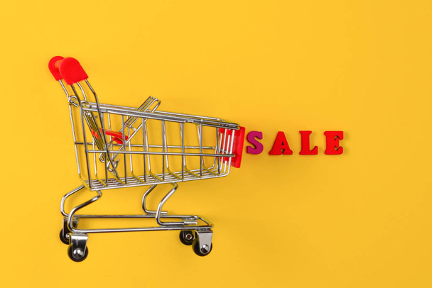 Sale text and shopping cart on a yellow background.  - Photo, Image