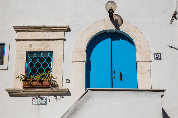 Μπλε πόρτα και παράθυρο στον λευκό τοίχο  - Φωτογραφία, εικόνα