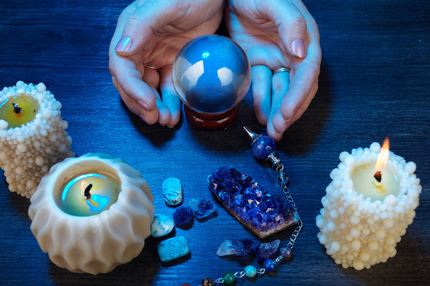 hands of a fortune-teller working with a crystal ball in blue light - Фото, зображення