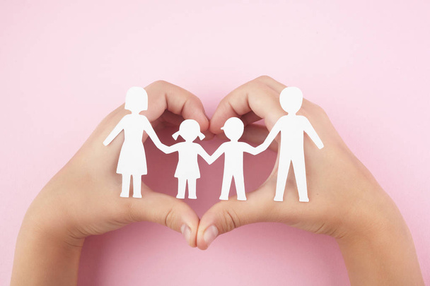 Paper family in child hands on pink background. Top view - Foto, Imagen