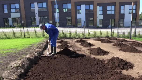 Townhouse owner man work in yard with rake tool. Level fertile soil. Static shot - Footage, Video
