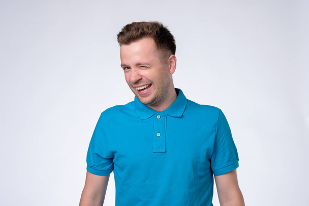 Happy Sly man in blauw t-shirt winking een oog - Foto, afbeelding