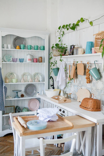 Stylish and sunny interior of kitchen space with small wooden table at the photo studio. Scandinavian room decor with kitchen accessories. - 写真・画像