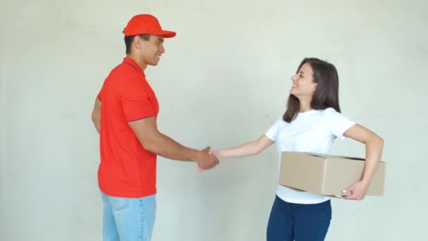 Pracownik doręczeń w mundurze dostarczanie paczek do kobiety. Mężczyzna trzymający pudełka, uśmiechnięty i uścisk dłoni - Materiał filmowy, wideo