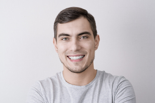 Close-up portrait of European man with perfect white smile isolated on grey background - Photo, Image
