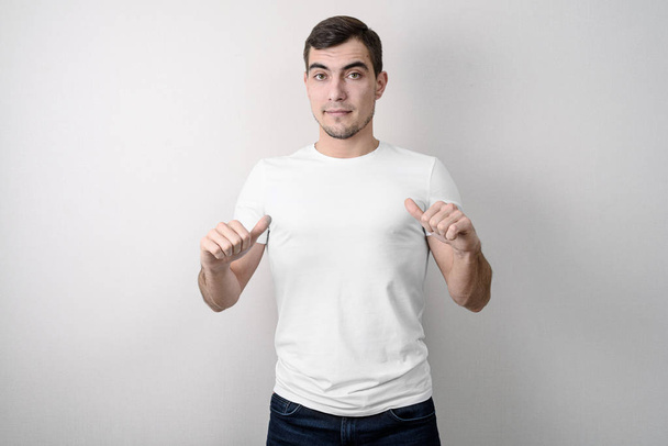 Hombre europeo con cara confiada muestra camiseta blanca en blanco
 - Foto, imagen