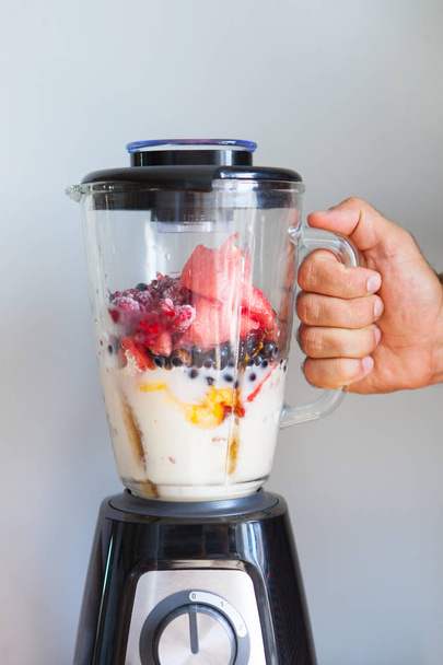 A blender filled with fresh whole fruits for making a smoothie o - Foto, Imagen