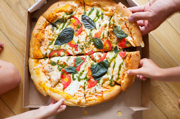 Jantar em grupo familiar. Mãos a tomar fatias de pizza com caixa. Frita.
 - Foto, Imagem