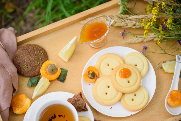 Tasty shortbread, apricot jam, ginger, fragrant tea, lemon, in the summer cottage style - Fotoğraf, Görsel