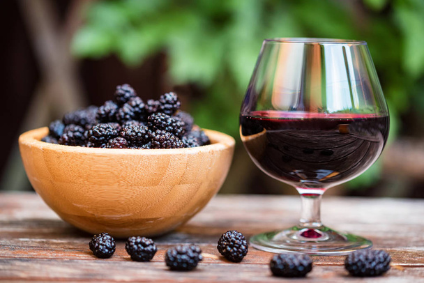 Chiudi gelsi freschi frutta in ciotola e vino in vetro - Foto, immagini